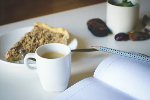 Fatia de bolo num prato ao lado de uma xícara de café